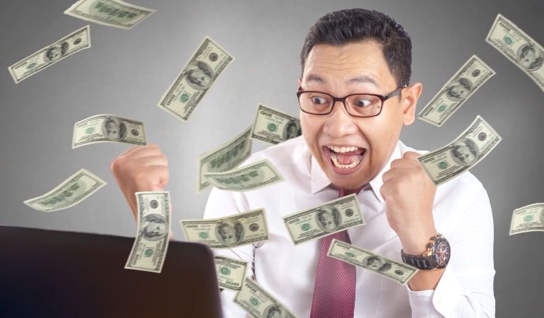 Excited man in shirt catching dollar notes that are floating in the air